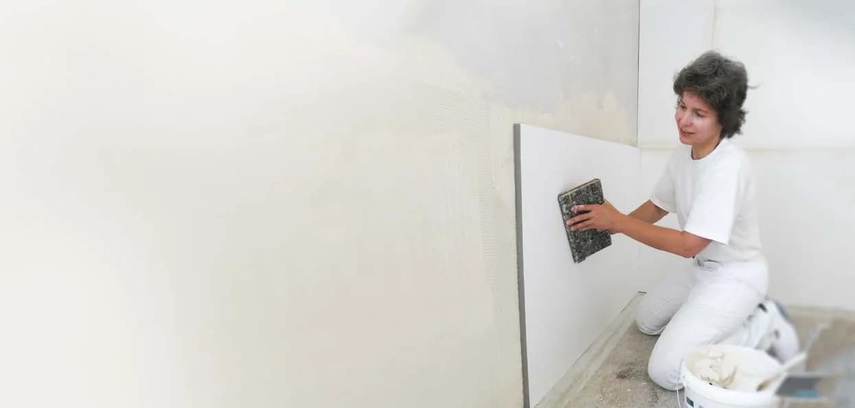 Malerin drückt eine Korff-Dämmplatte zur Innendämmung mit dem Reibebrett an die Wand